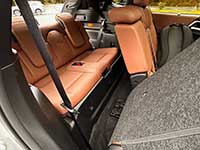 2026-Outlander-PHEV-seating - Micro News - Calgary - Alberta - Canada Cargo area of a car with orange-brown leather rear seats folded down, gray carpeting, and a visible seat belt.